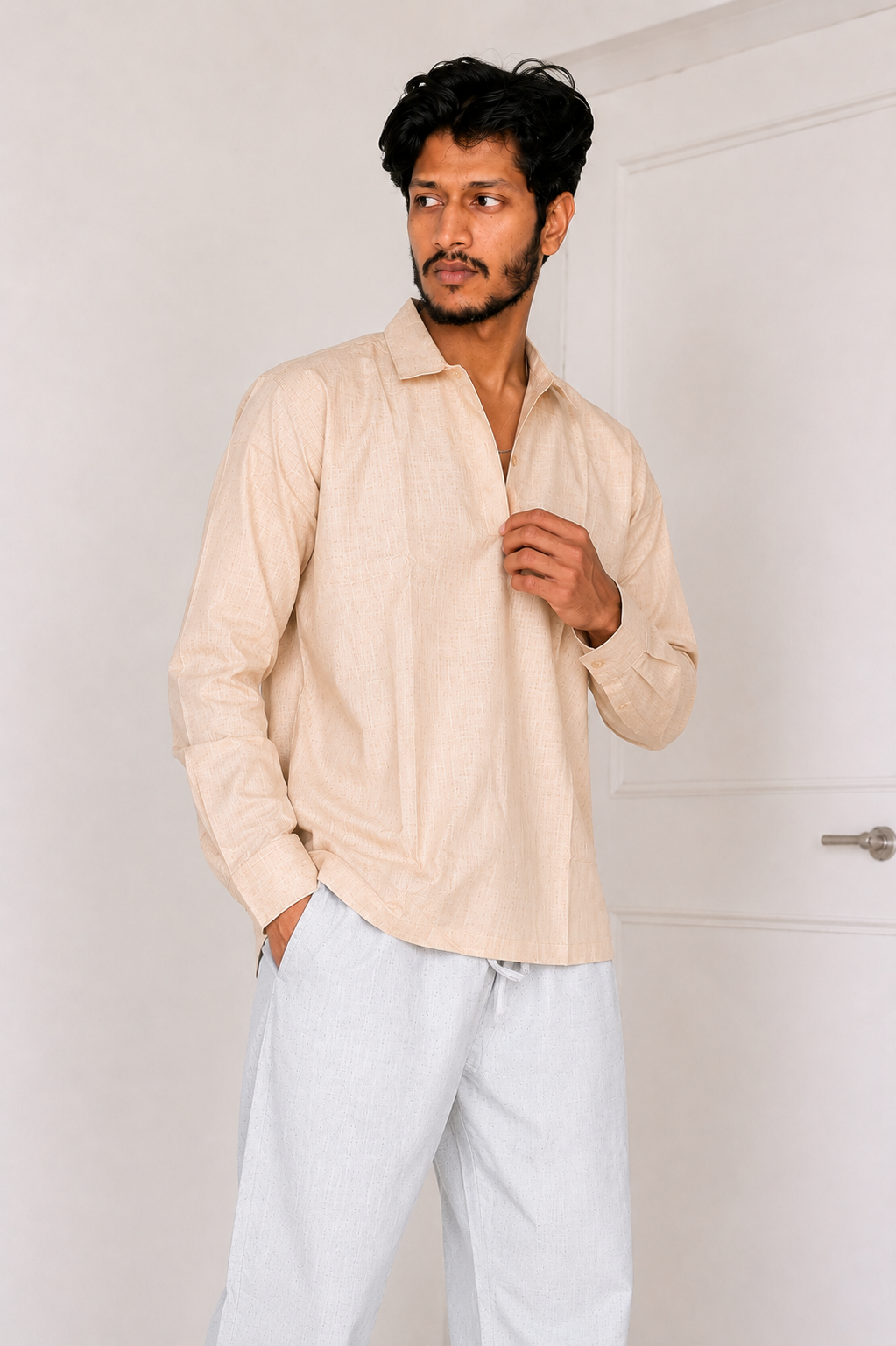 Man wearing a beige shirt and light blue pants against a white background